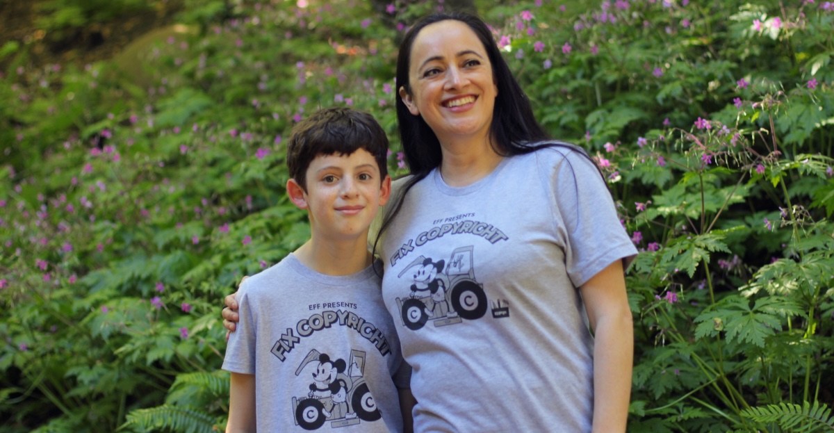 Woman and child wearing EFF's Fix Copyright t-shirt. Grey shirt with Steamboat Willie fixing a tractor