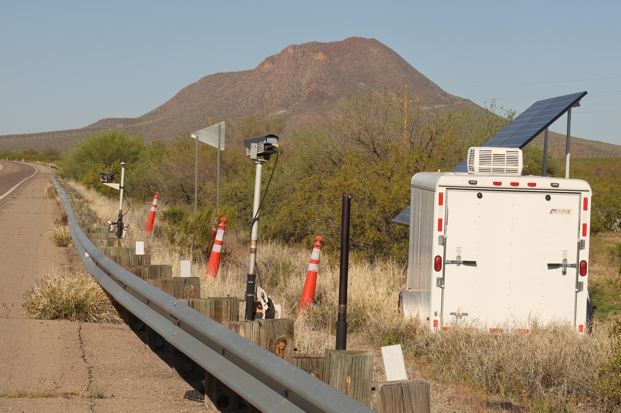A series of cameras next to a trailer by the side of the road. A series of cameras next to a trailer by the side of the road.