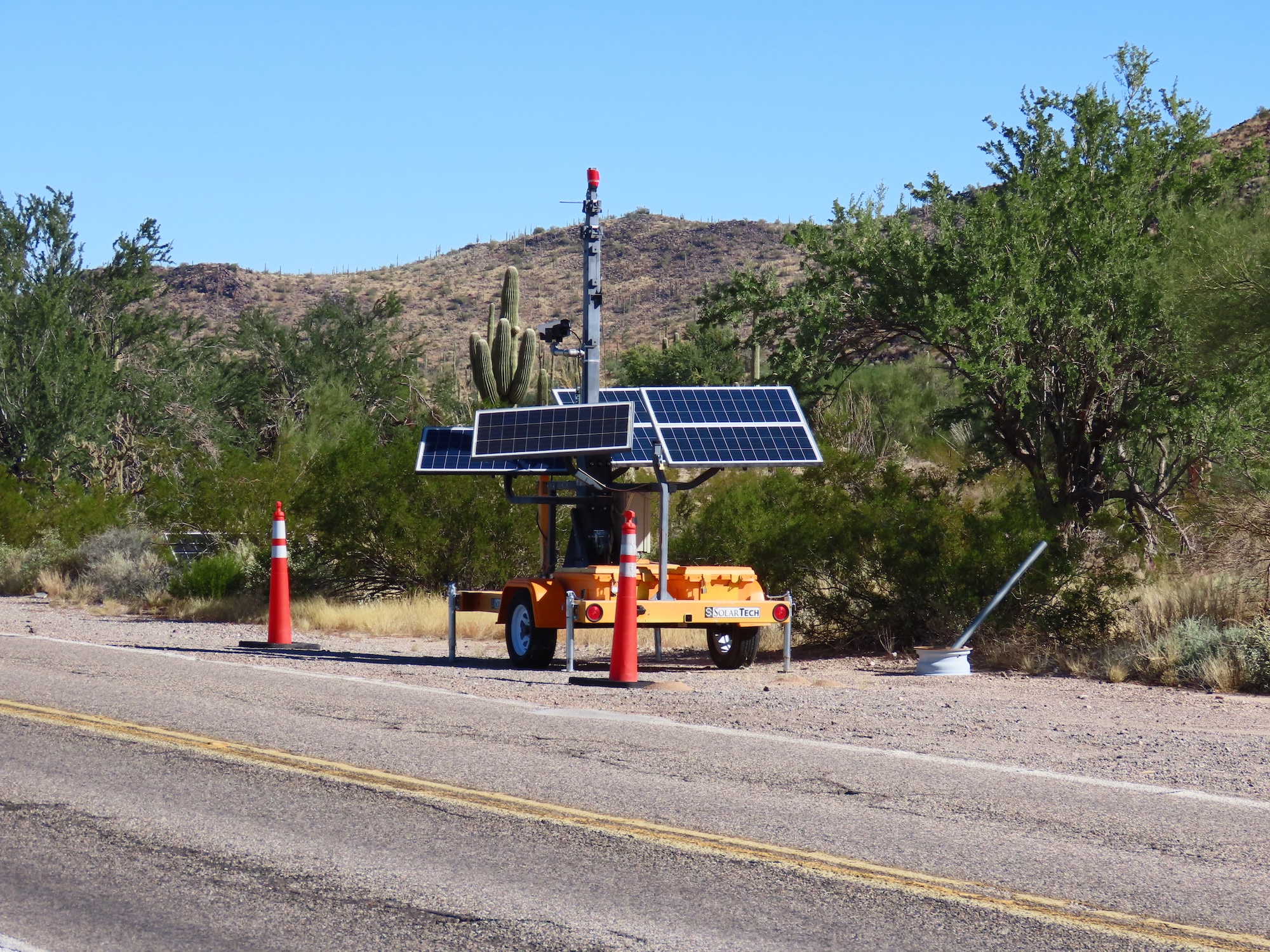 An orange trailer with ALPR cameras by the side of the road. An orange trailer with ALPR cameras by the side of the road.