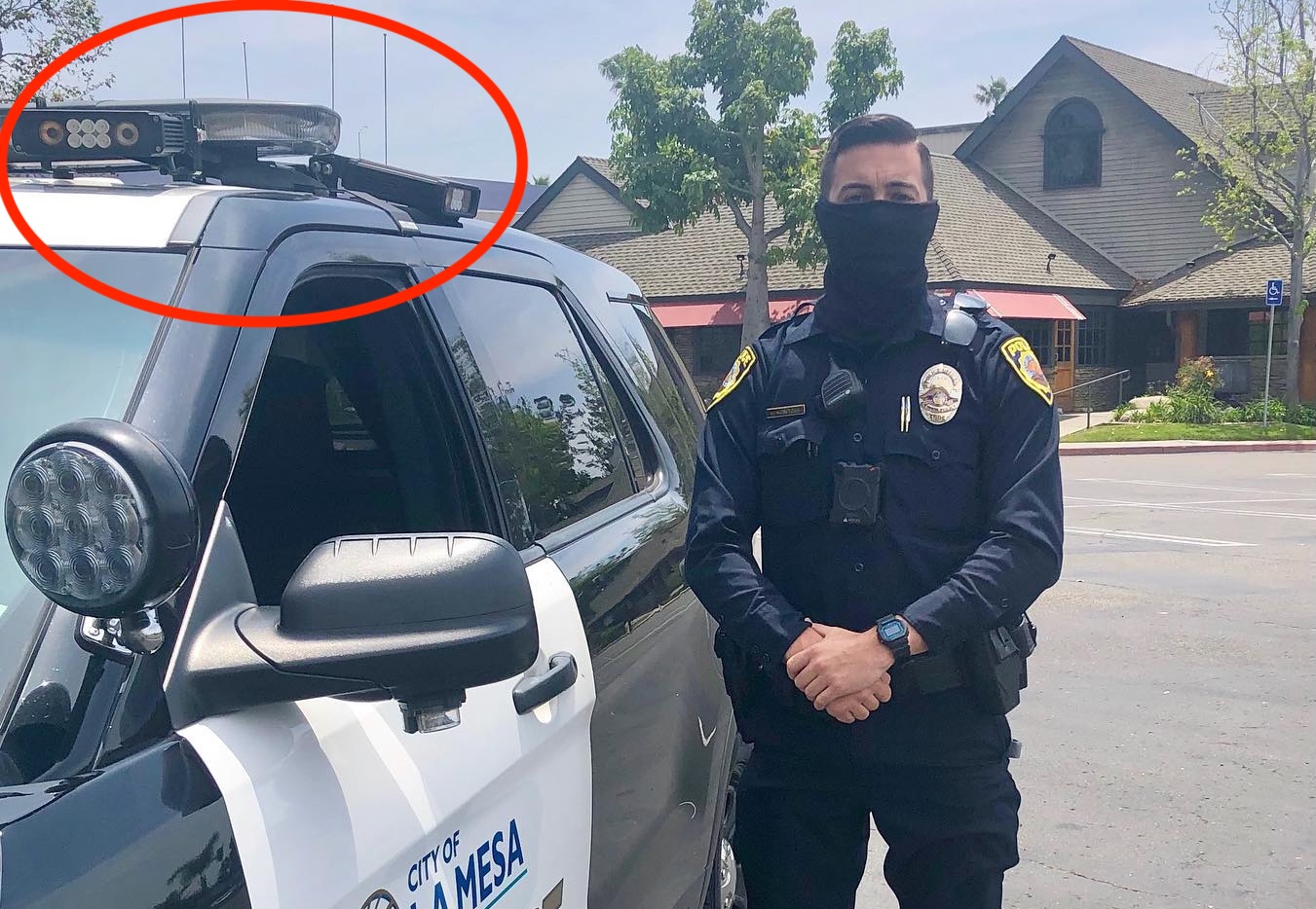 A masked police officer stands next to a patrol vehicle with two ALPR cameras. A masked police officer stands next to a patrol vehicle with two ALPR cameras.